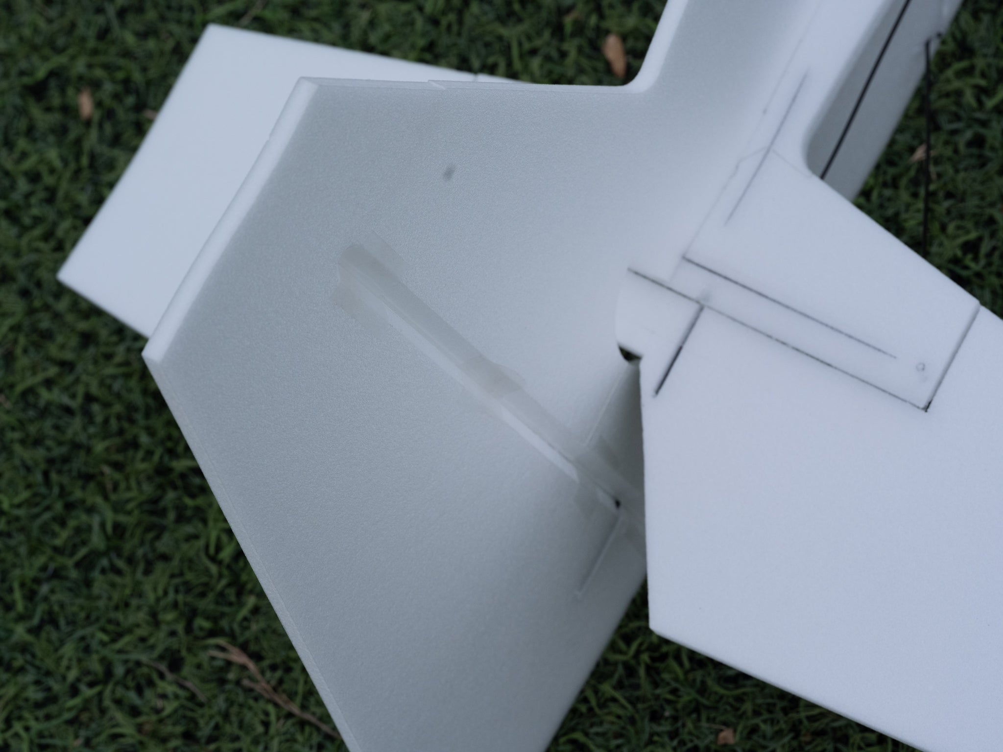 Close-up of a white model airplane wing on grass
