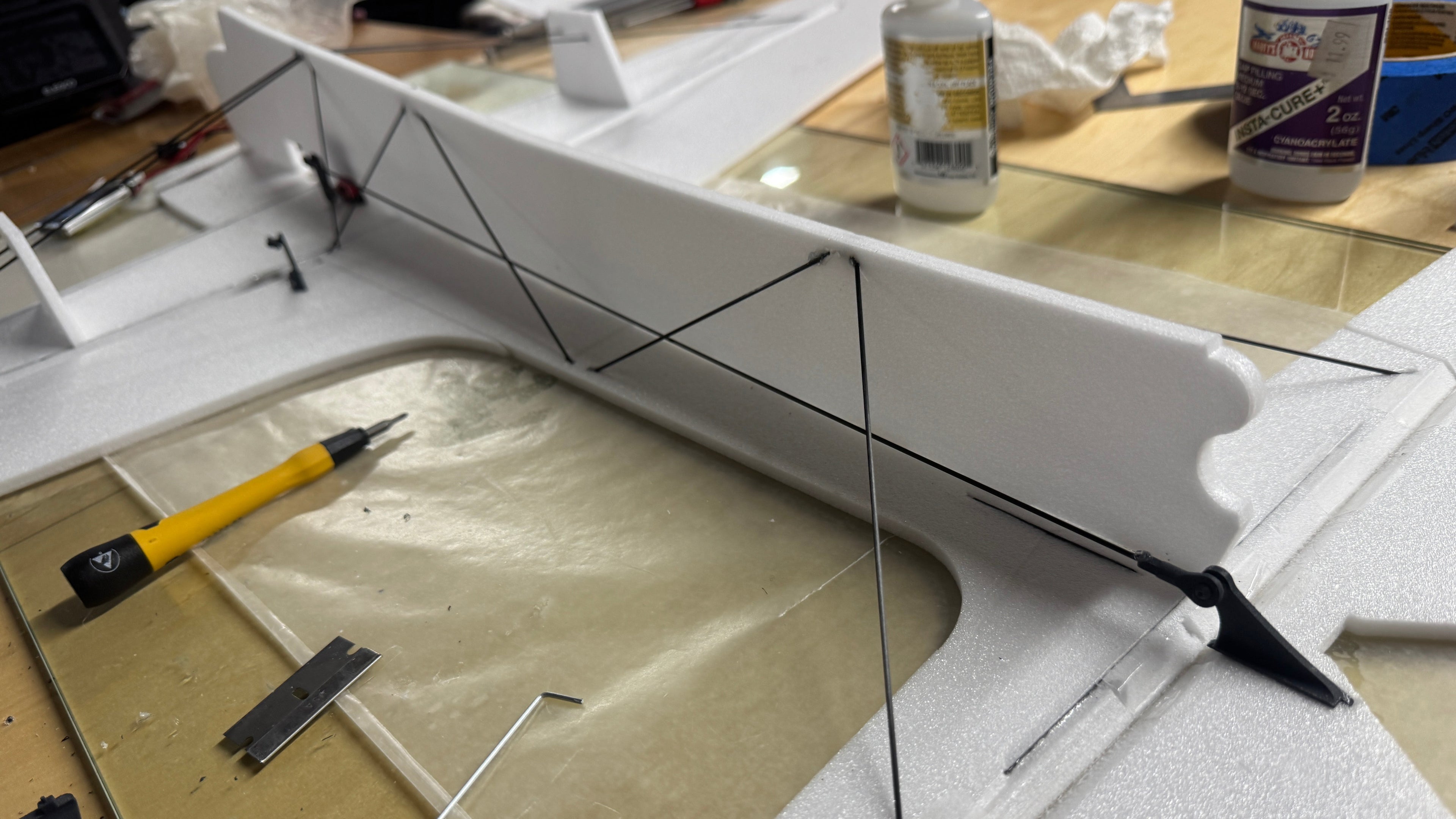 Model airplane on a workbench with tools and glue bottles