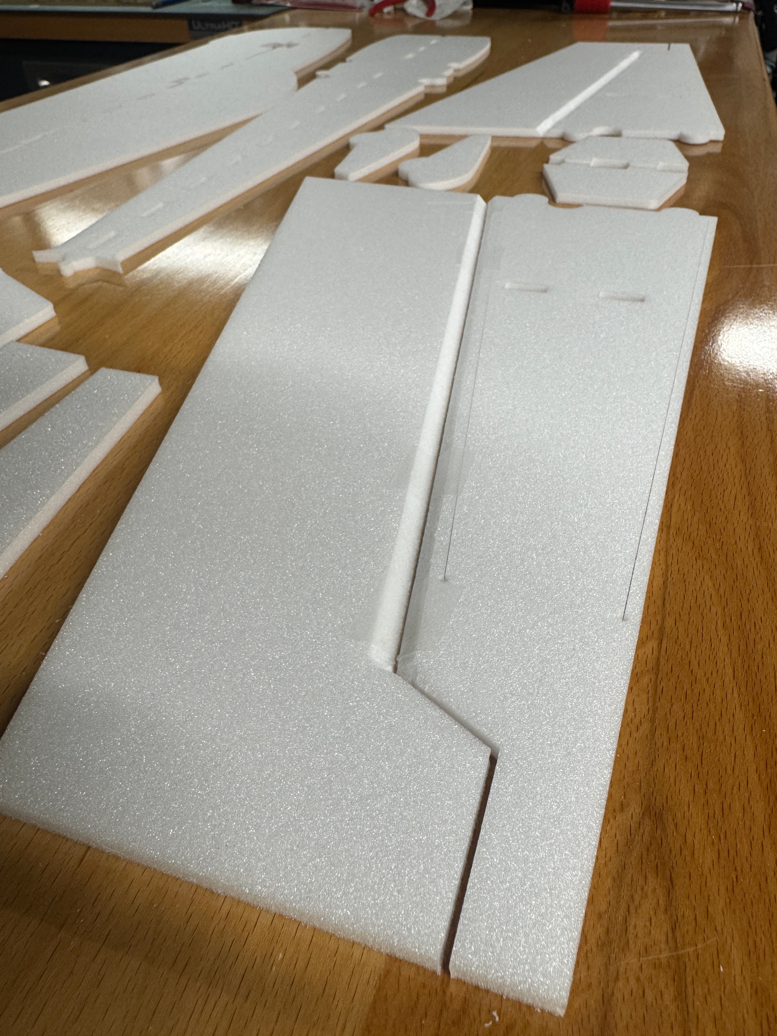 White foam board cut into various shapes on a wooden surface