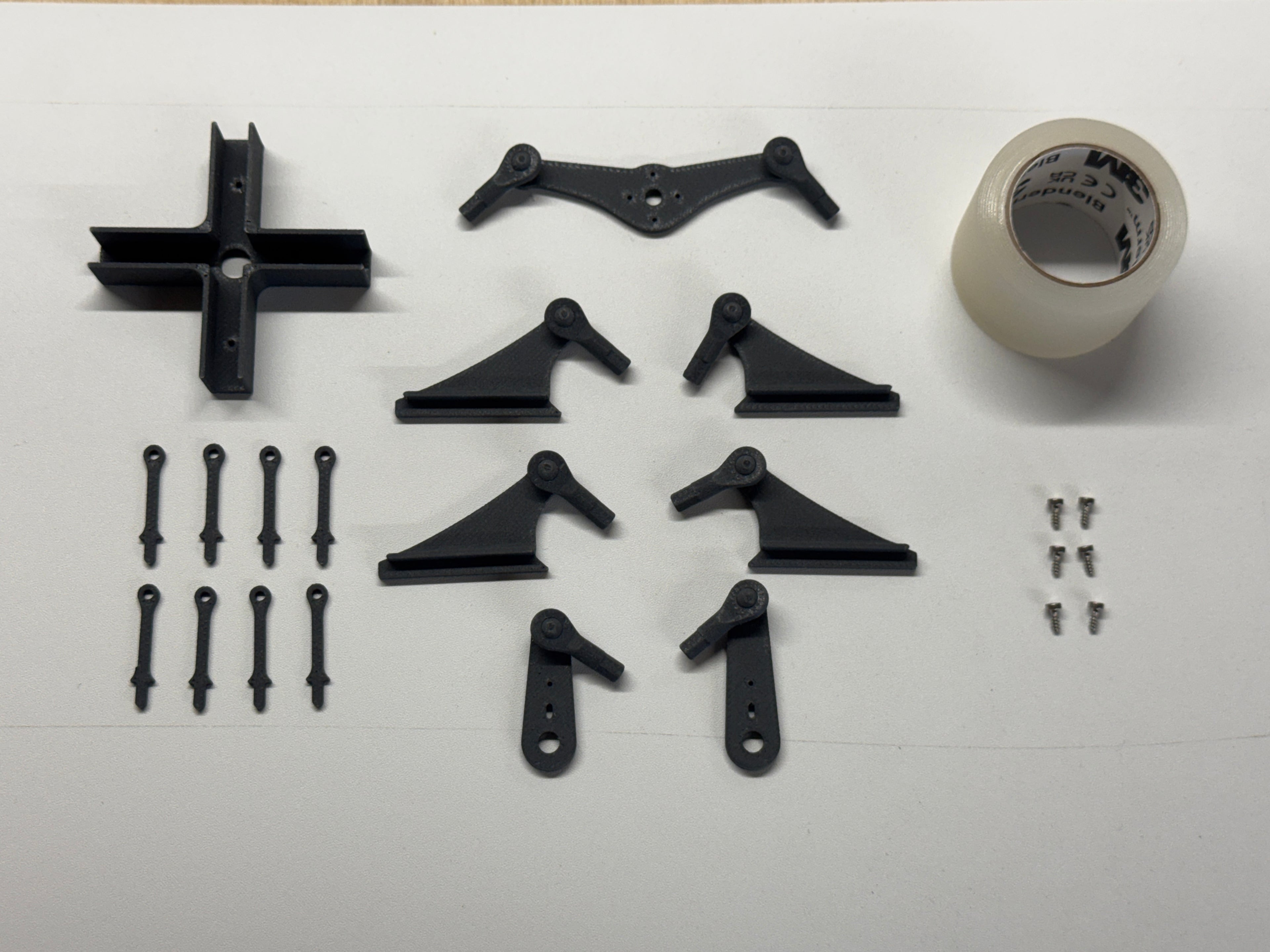 Black mechanical parts and a roll of tape on a white background