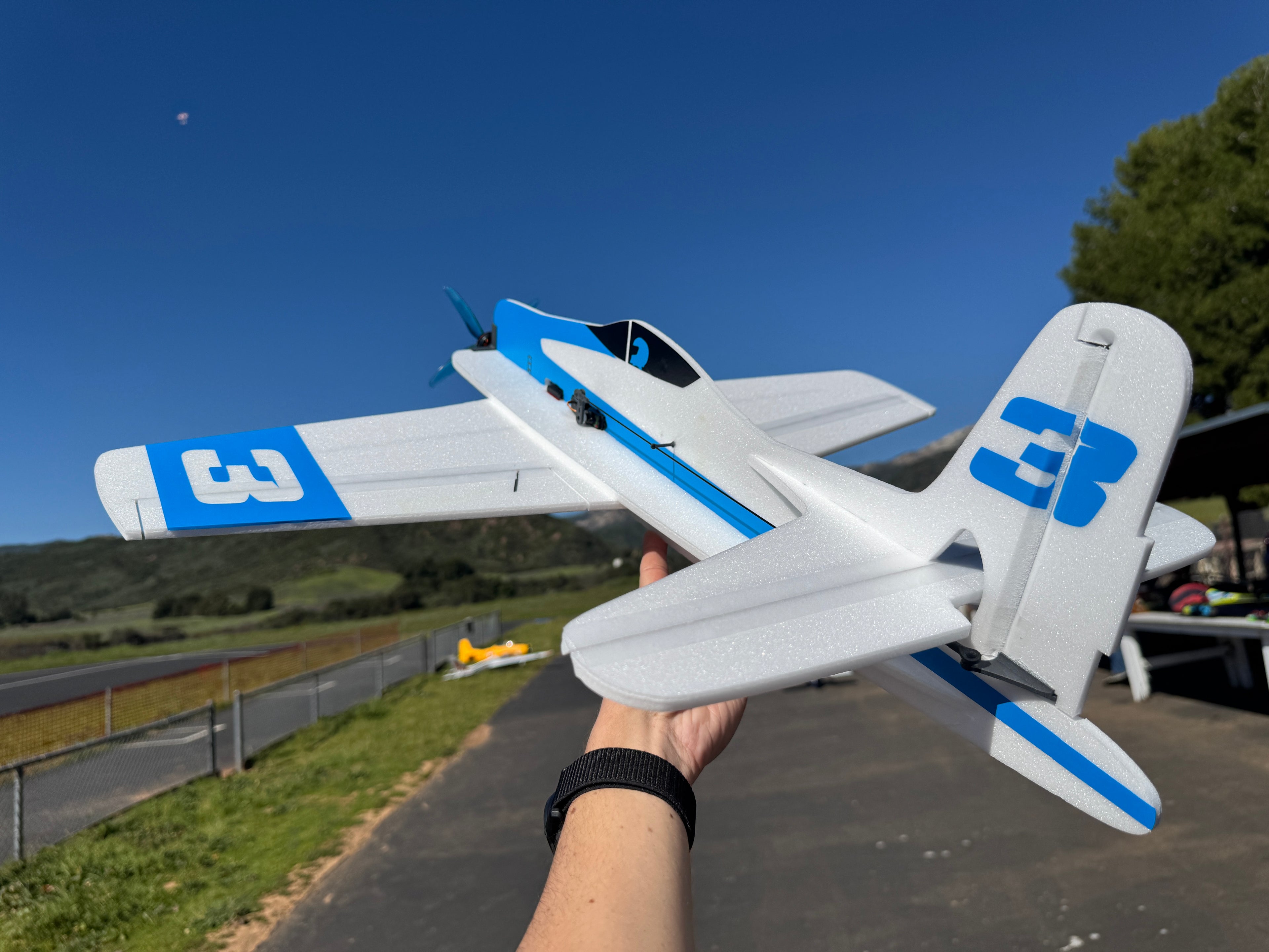 Model airplane with a visible logo held by a person outdoors.