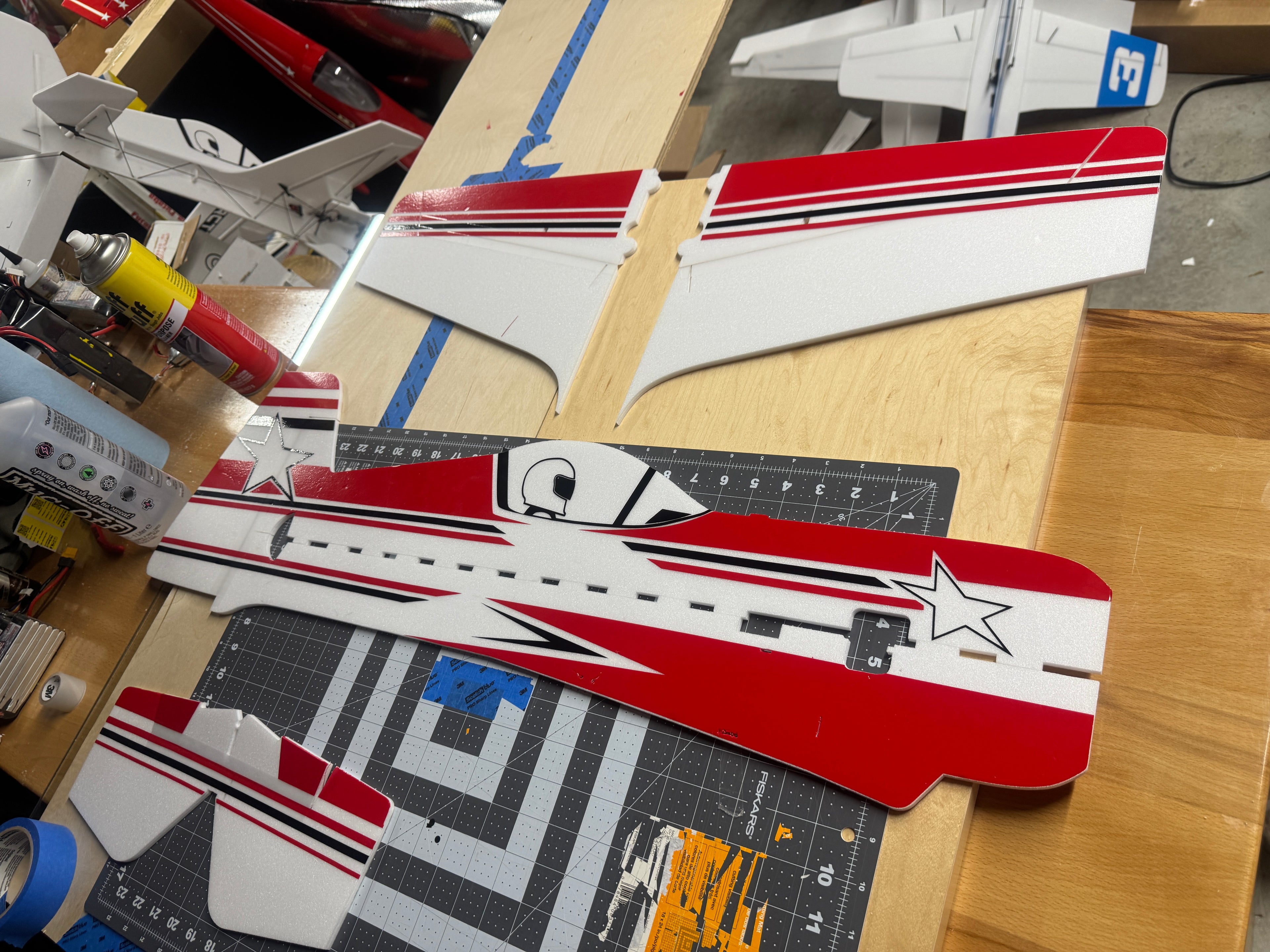 Model airplane parts on a wooden table with tools and materials.