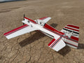Model airplane with red and white design on a dry, cracked earth surface