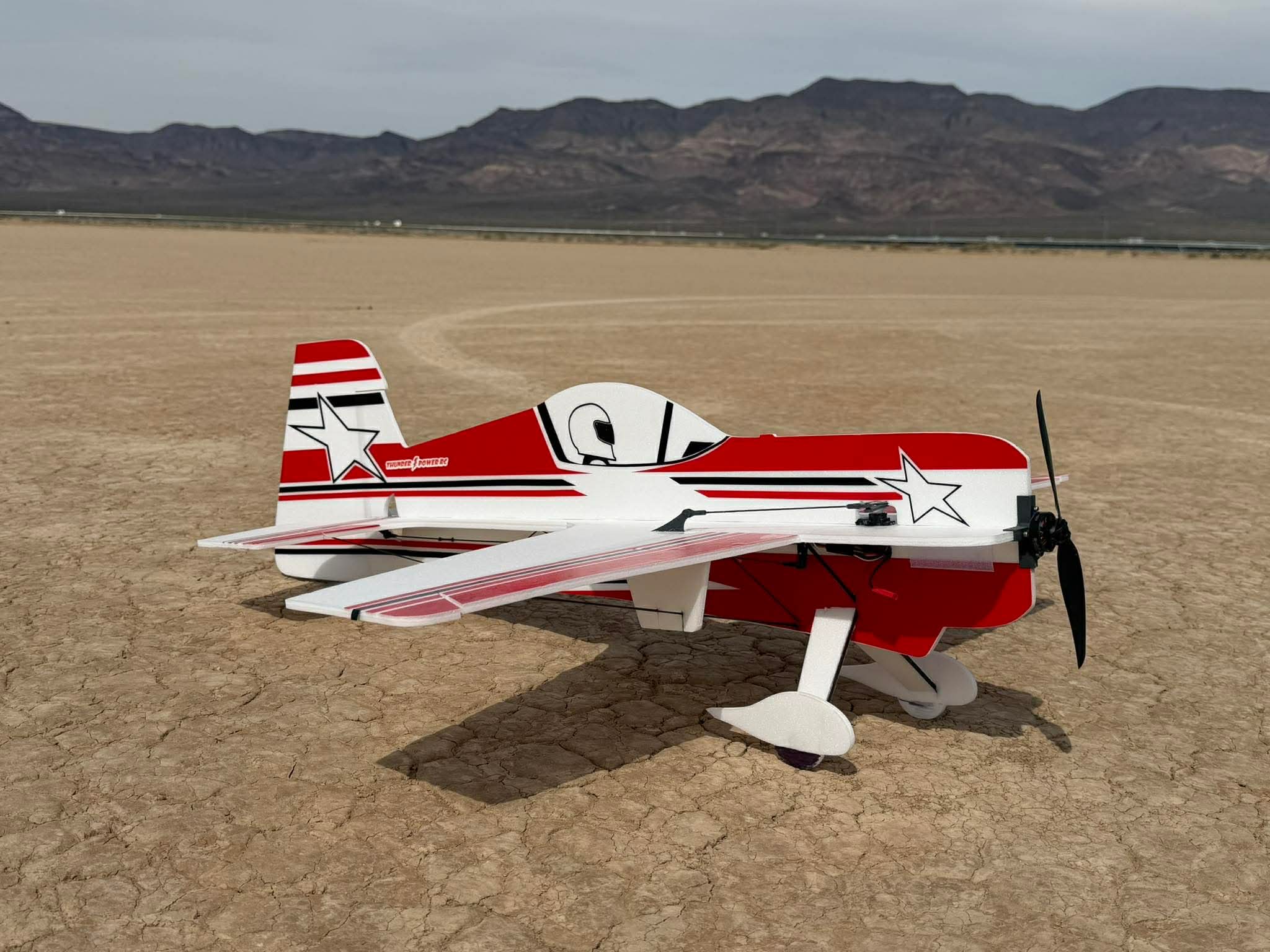 Red and white airplane with star design on a desert landscape