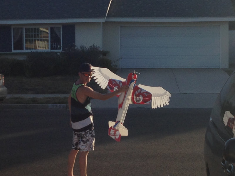 Tomas holding a foamie with Angel Wings also made out of foam attached to the plane
